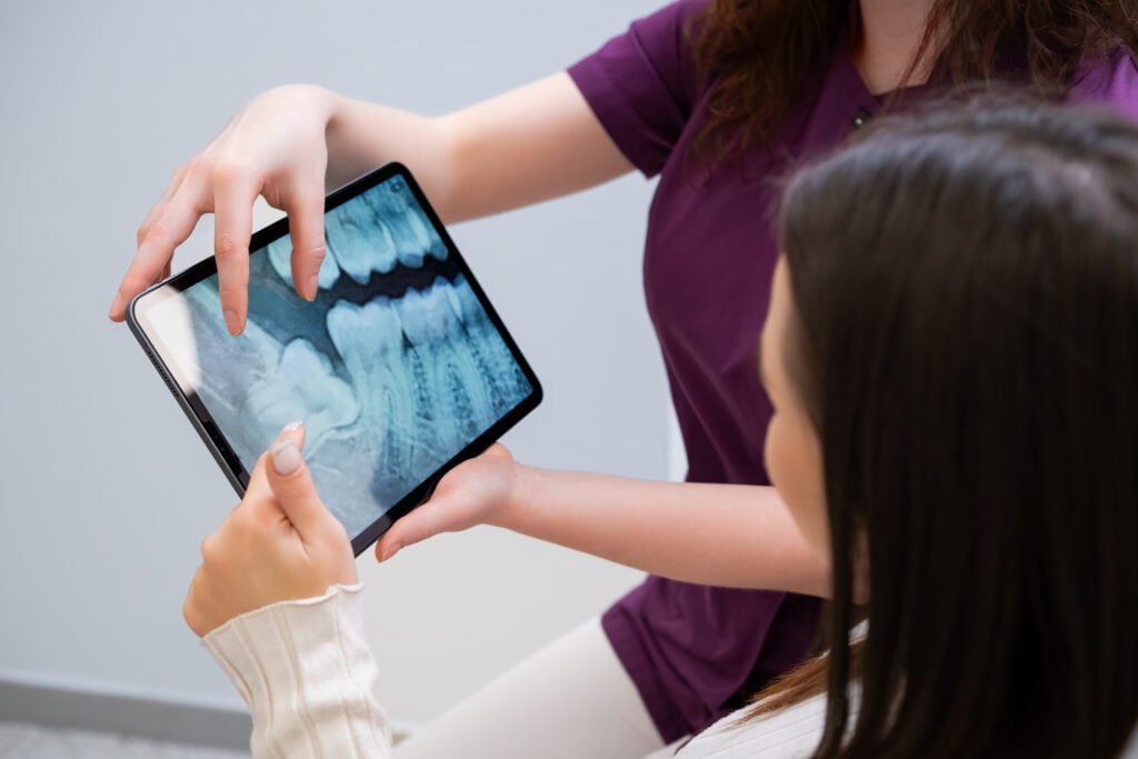 Dentist discussing tooth extraction procedure with patient showing xrays