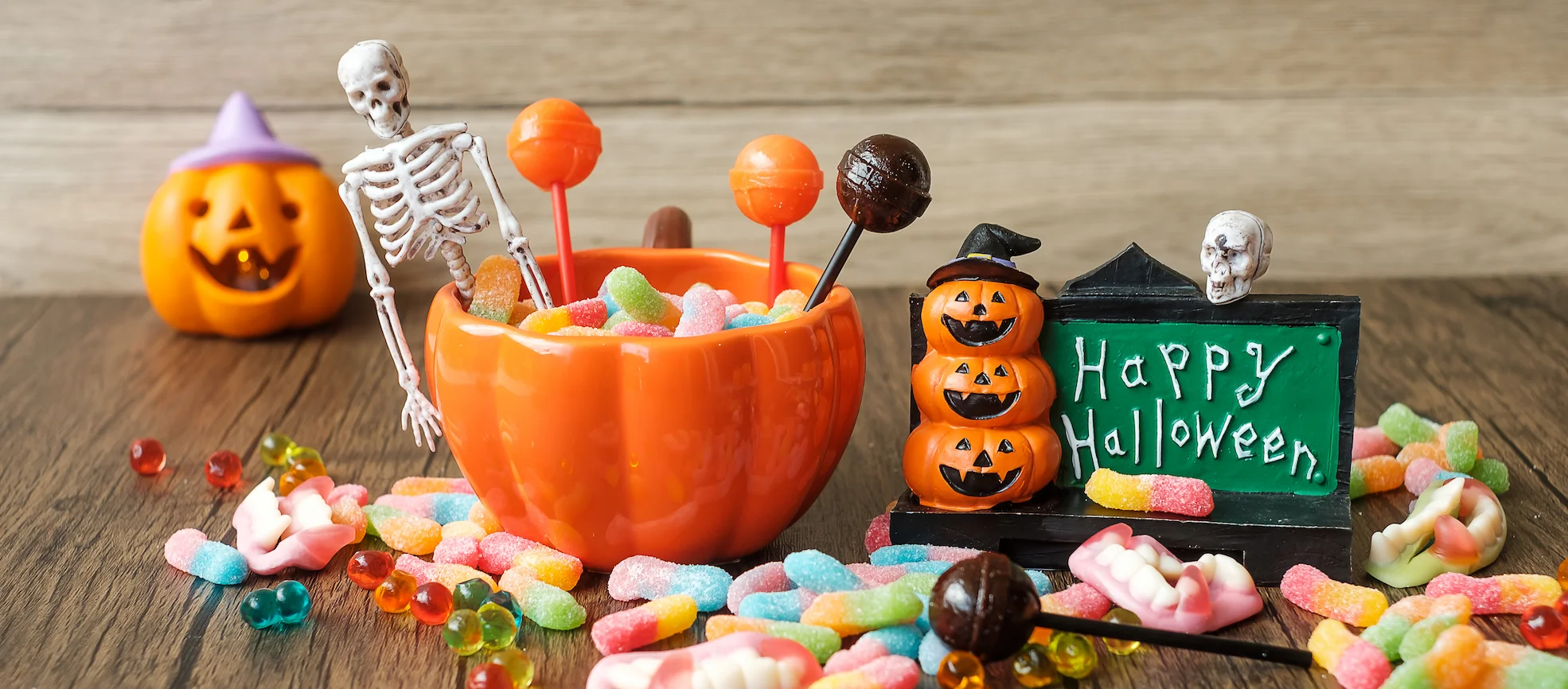 Tazón con dulces de Halloween rodeado de gomitas y decoraciones, representa el riesgo de dulces y caries en esta temporada.